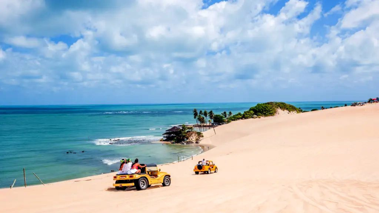 A family joyfully traversing the picturesque coastal landscape aboard a vibrant off-road buggy, the sun's golden rays casting a warm glow over the serene scene. Lush palm trees and verdant foliage frame the middle ground, while the distant horizon showcases the shimmering turquoise waters of the Maragogi coastline. The buggy's sturdy frame and large wheels navigate the sandy terrain effortlessly, conveying a sense of adventurous exploration. The expressions of delight on the passengers' faces reflect the exhilaration of this personalized, immersive experience tailored to diverse audiences.